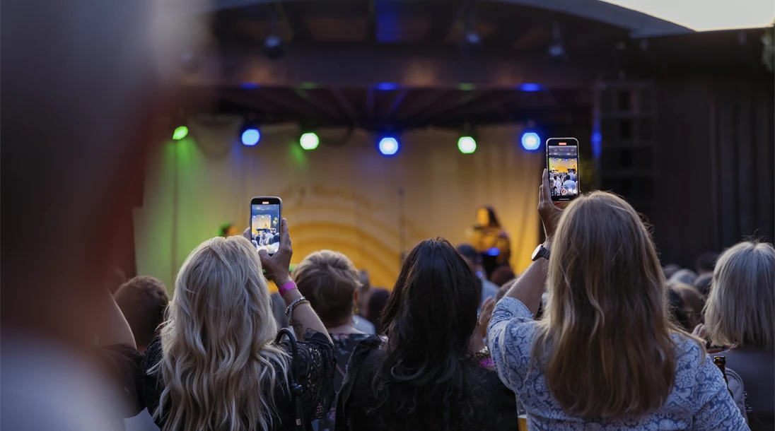 Kvinnor filmar konsert med sina mobiltelefoner, i bakgrunden syns andra besökare och scen