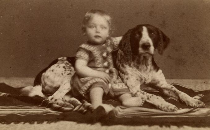 Foto av ett barn som sitter och håller armen om en hund, ur CE Nygrens porträttsamling