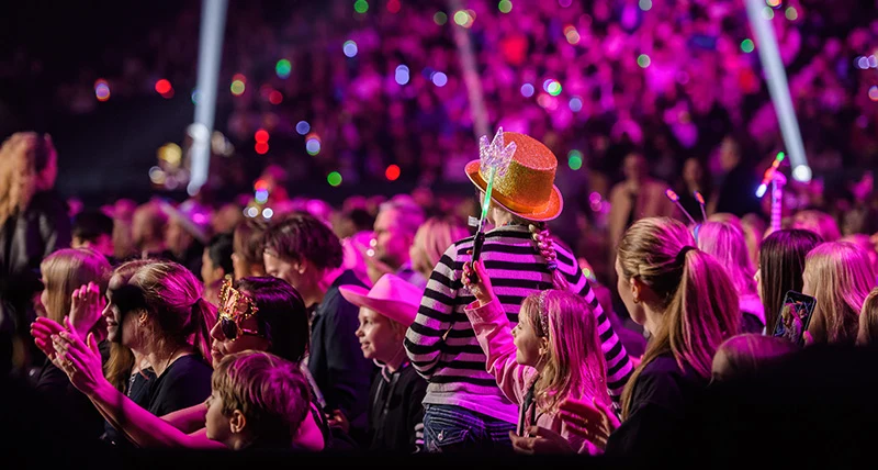 Människor i en publik med fokus på en flicka med glittrig hatt.