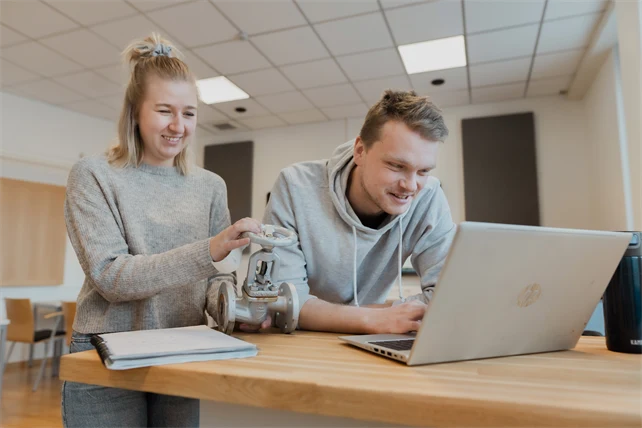 Två personer i ett klassrum med en laptop 