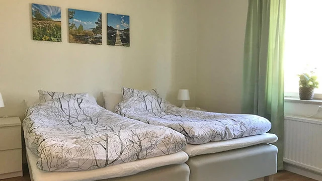 två enkelsängar står bredvid varandra mot en ljus vägg med tre tavlor