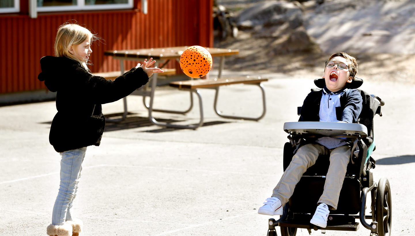 Flicka som kastar en boll till en pojke i rullstol