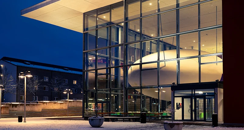 En stor byggnad med glasfasad avslöjar ett äggformat föremål