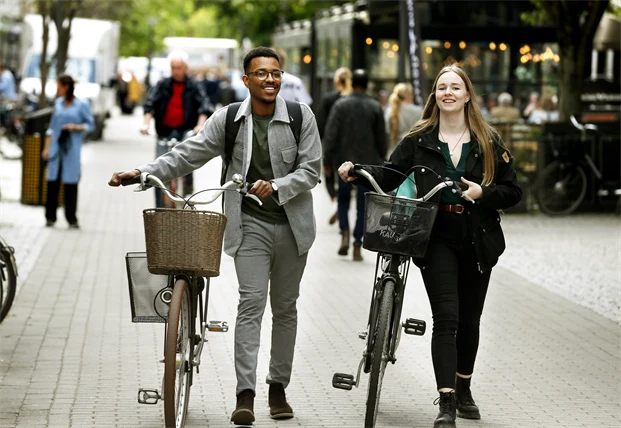 Två personer går med sina cyklar.