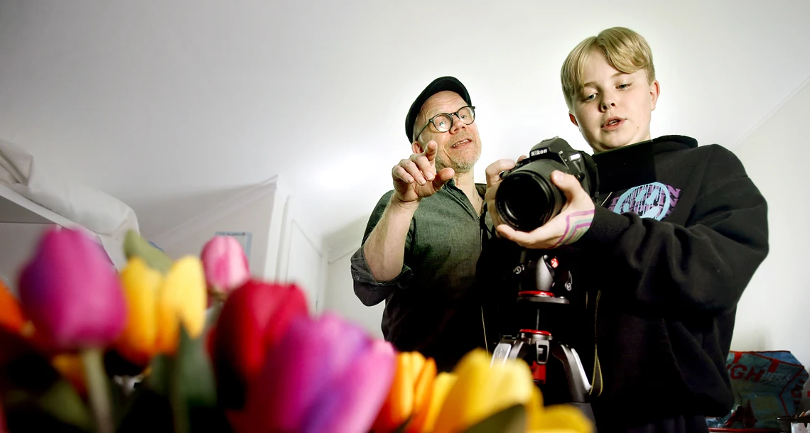 Pojke och lärare fotar blommor inomhus 