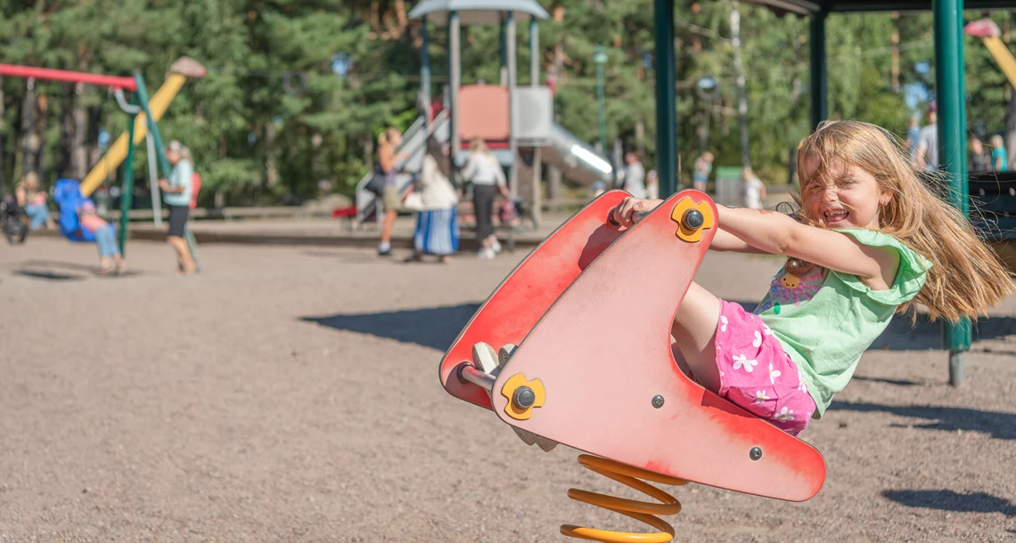 Flicka på gunghäst i lekpark. 