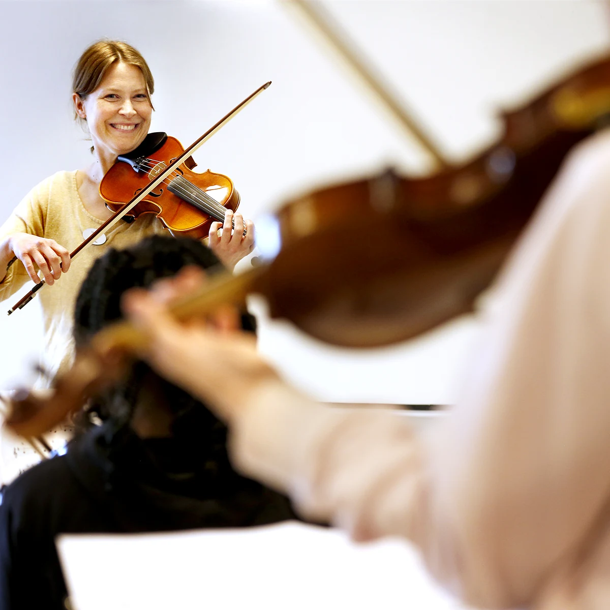 Två elever och en lärare som spelar fiol i ett klassrum
