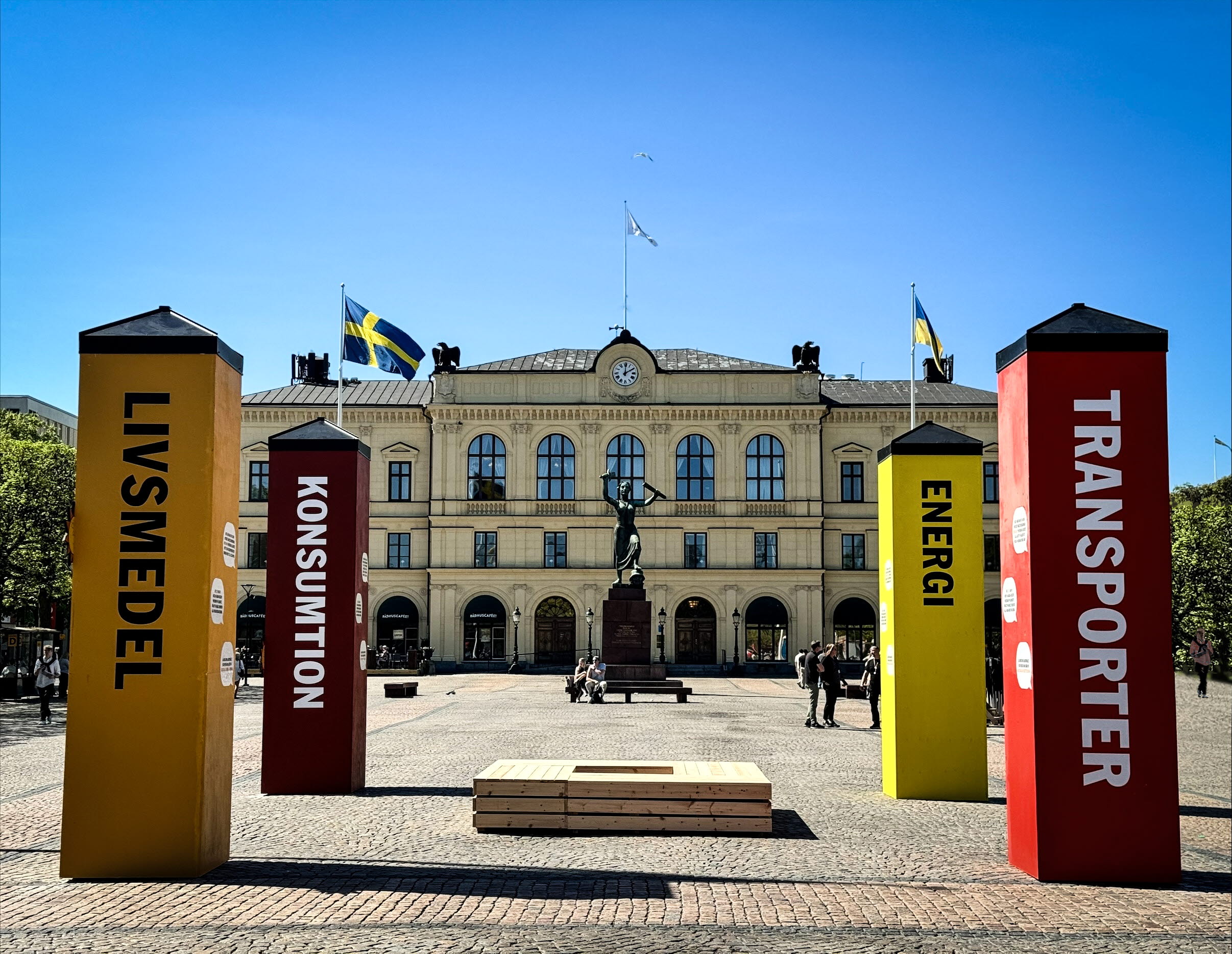 Två markdekaler med fyra färgglada staplar framför entrén till Kronoteket