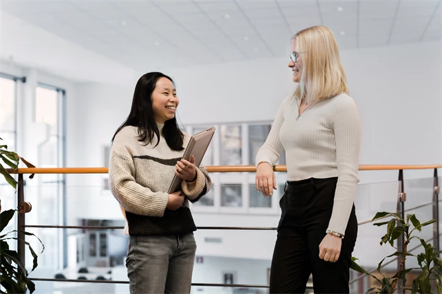 Två personer ler mot varandra. En har en laptop i famnen.