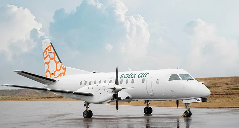 Ett vitt flygplan med en orange logotyp på bakre vingen står på en landningsbana.
