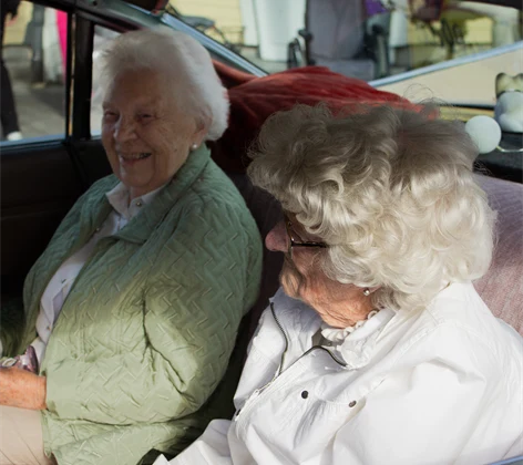 Två kvinnor sitter i baksätet på en rosa Cadillac