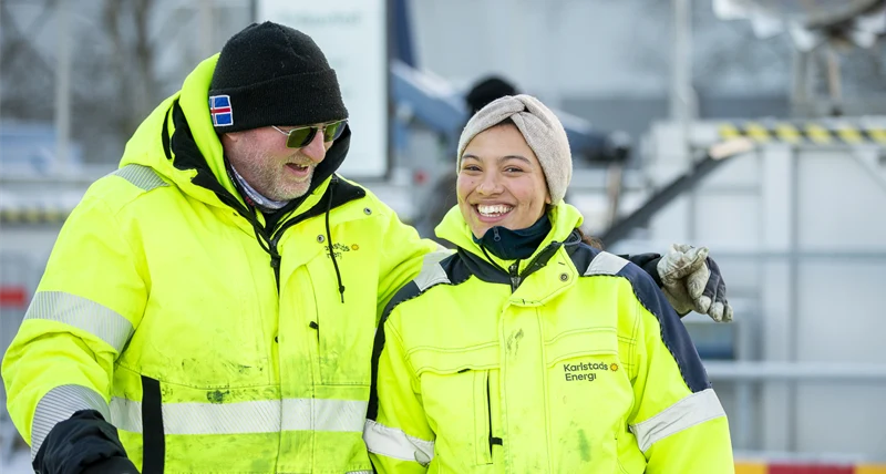 Två glada medarbetare i arbetskläder.