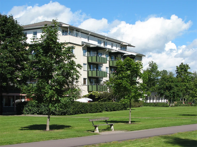 Lummig grönska och en blå himmel med lätta moln. Du ser en huskropp sticka upp i grönskan