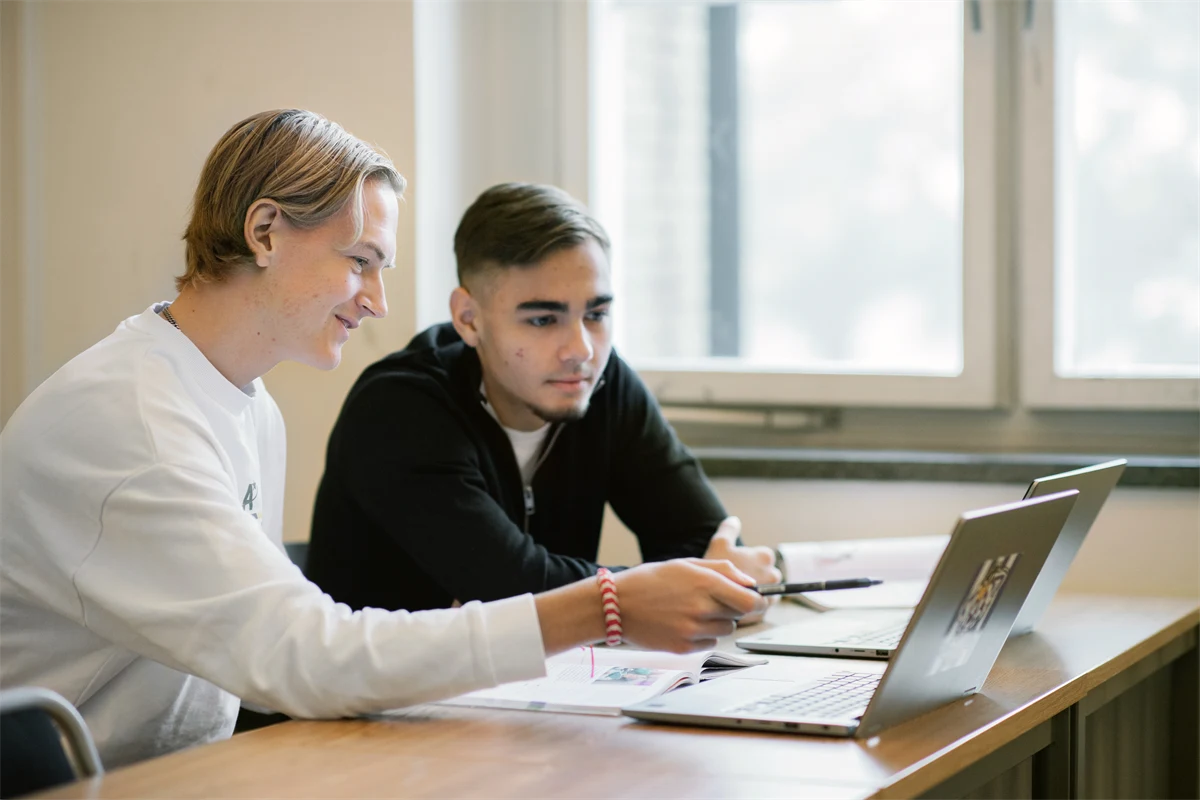 Två gymnasieelever pluggar tillsammans vid ett bord.