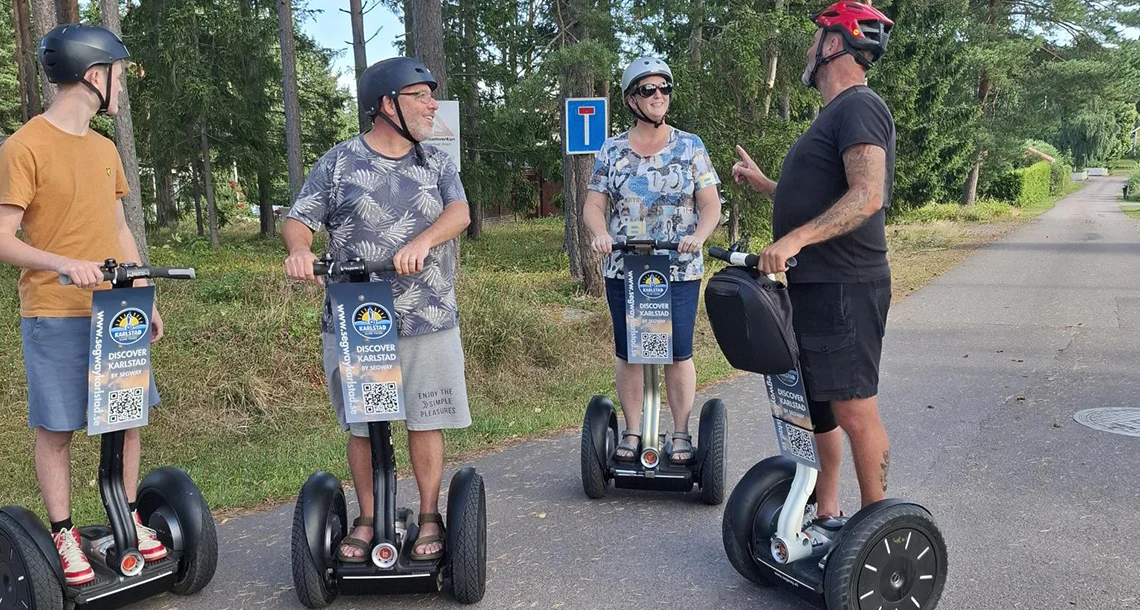 Fyra hjälmförsedda personer står på var sitt två-hjuliga fordon och pratar med varandra.