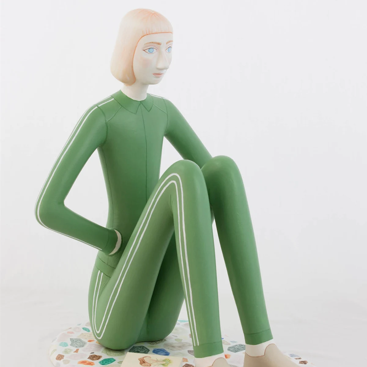 Konstverk Skulptur av sittande dam i gröna kläder av Sara Nilson.