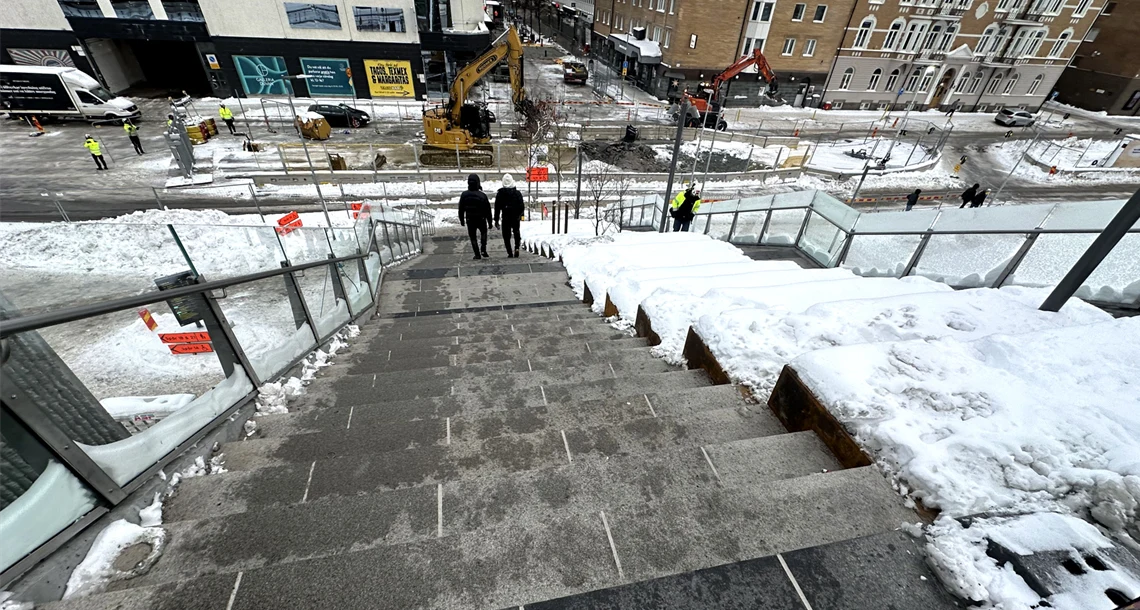 Bild på en trappa uppifrån. Två personer syns längst ner i trappan