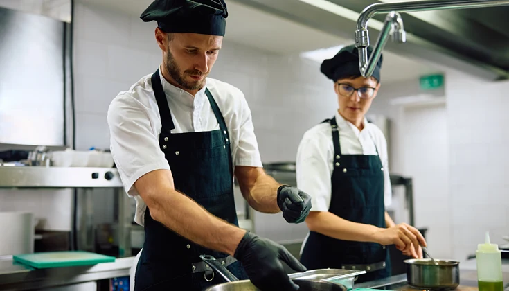 Två personer jobbar i ett restaurangkök