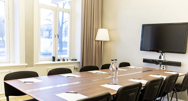 Ett mötesbord med åtta stolar och det står vattenflaskor och pappersblock på bordet.