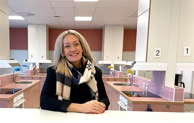 Ljushårig kvinna som sitter i ett rosa kök