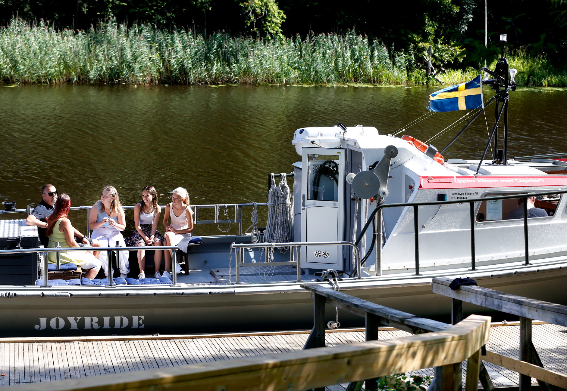 En familj med två vuxna och tre ungdomar sitter på en båt