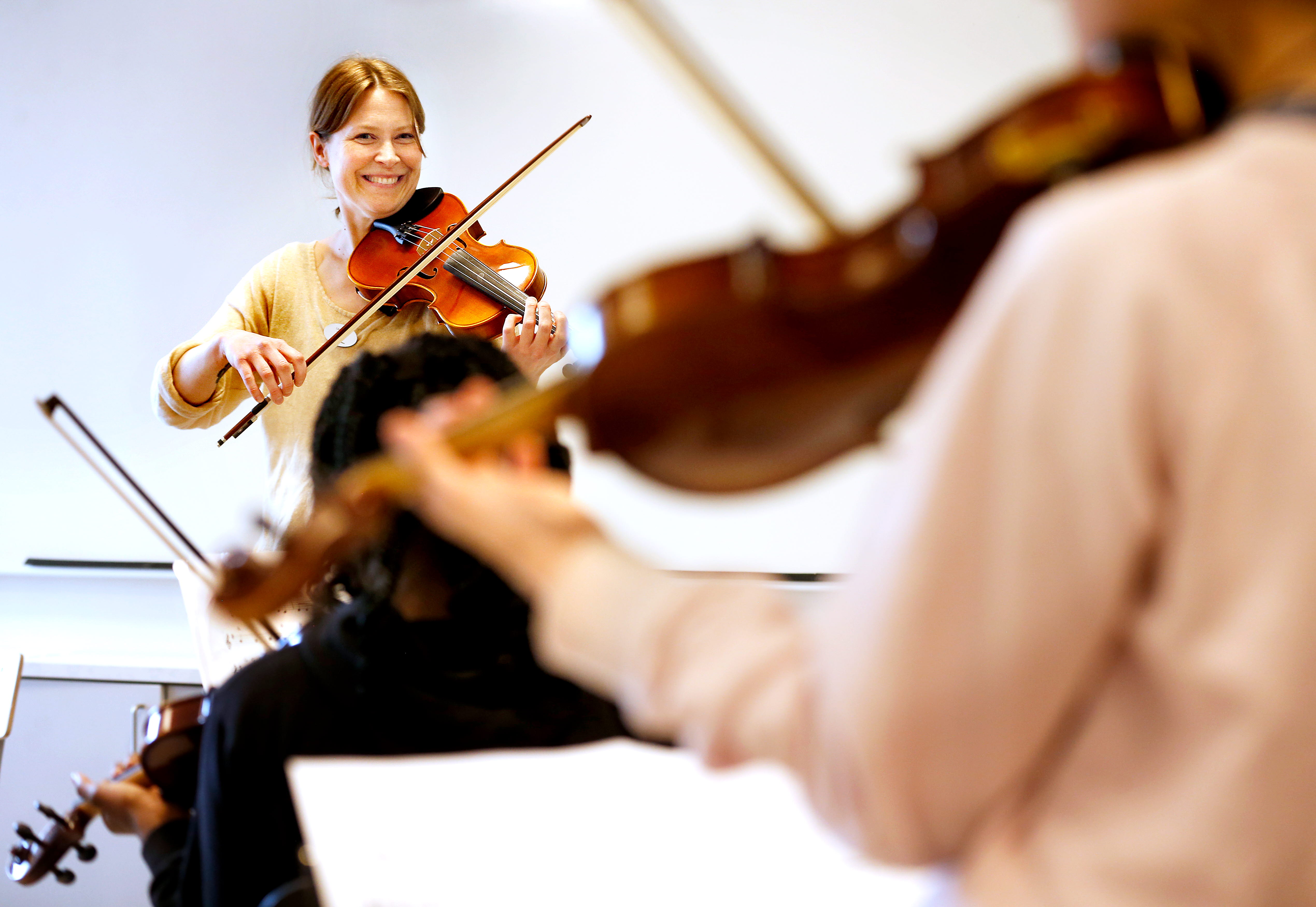 Två elever och en lärare som spelar fiol i ett klassrum