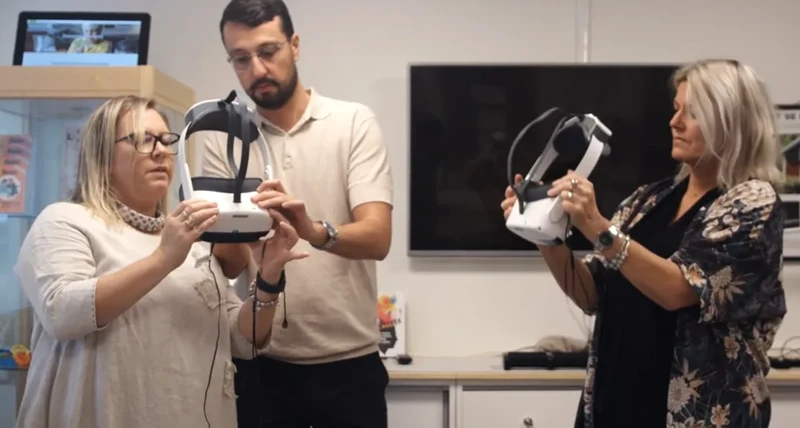 Två kvinnor och en man står med VR-utrustning i händerna