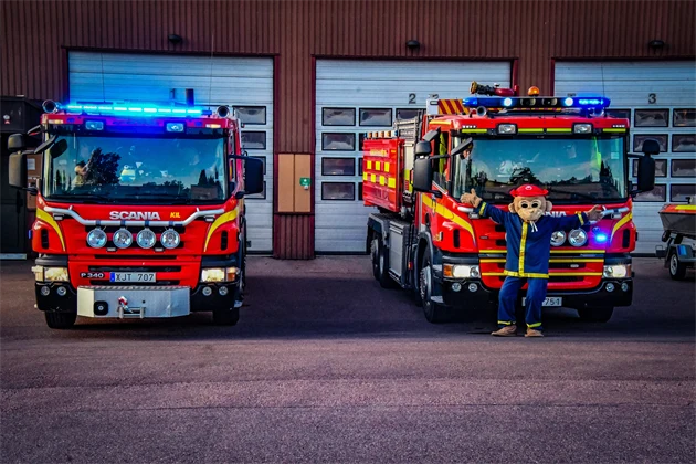 Två brandbilar och Flammy framför brandstationen i Kil.