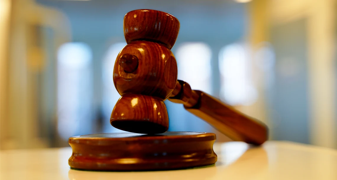 En ordförandeklubba i trä ligger på ett bord.