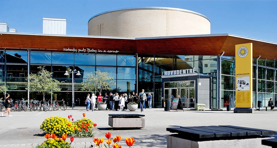 En stor byggnad med delvis en glasfasad med människor i förgrunden.