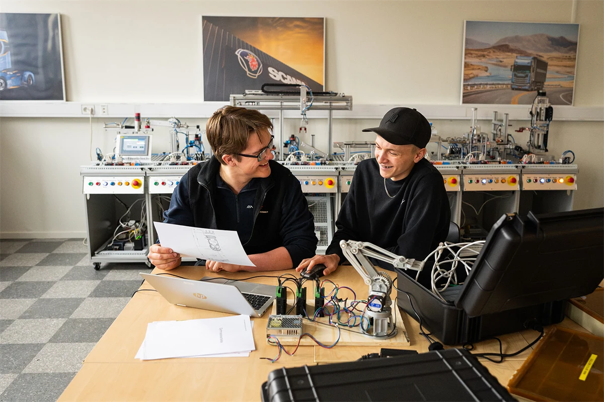 Två gymnasieelever sitter i ett klassrum med elutrustning