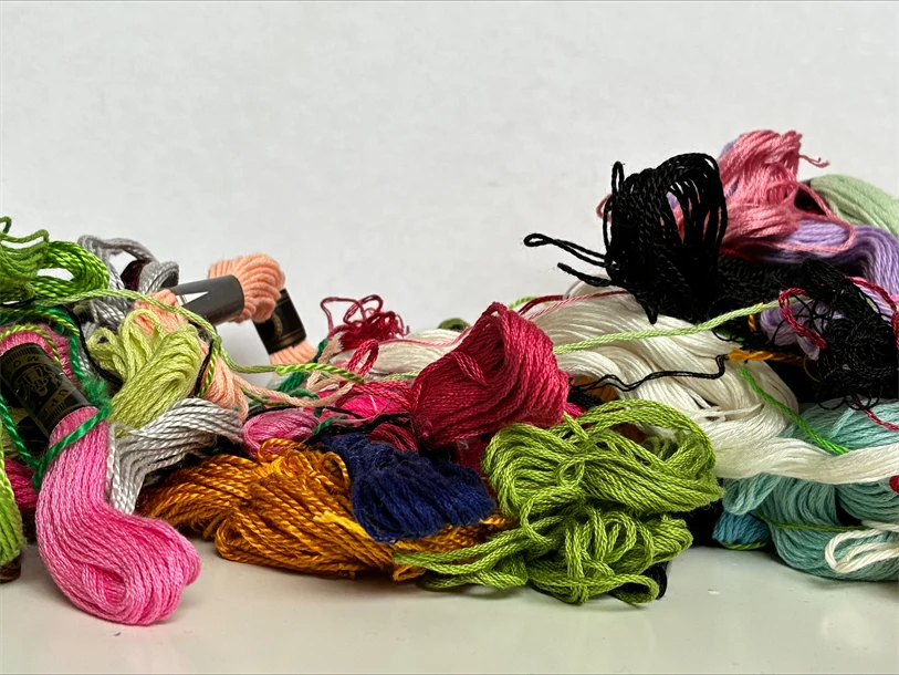 En hög med broderigarn i olika färger