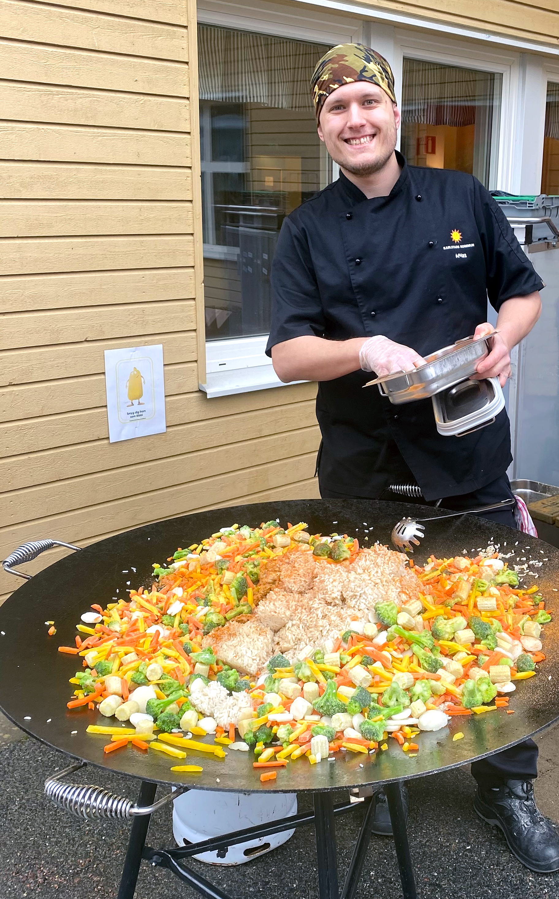 Kock som lagar mat på en wok utomhus