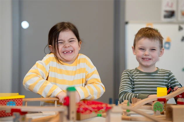 Pojke och flicka som är glada och bygger med klossar