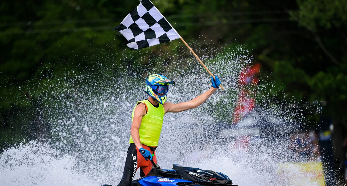 Person åker aquabike med målflagga i handen.