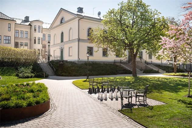 Bild på en park med Tingvalla vuxenutbildnings byggnader bakom