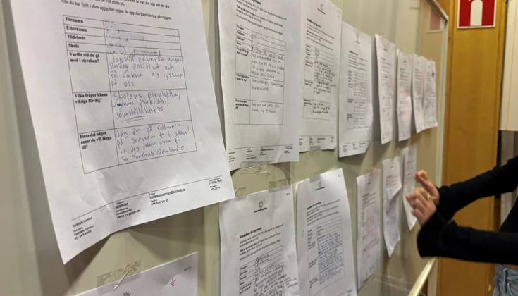 Ungdom sätter upp papper på en tavla.