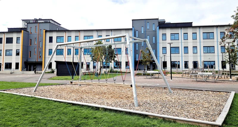Skolgård med en stor kompisgunga man kan sitta fler barn på.