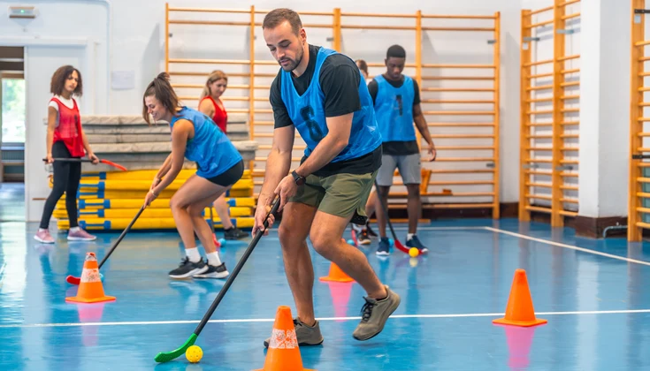 Personer spelar innebandy i en gymnastiksal.
