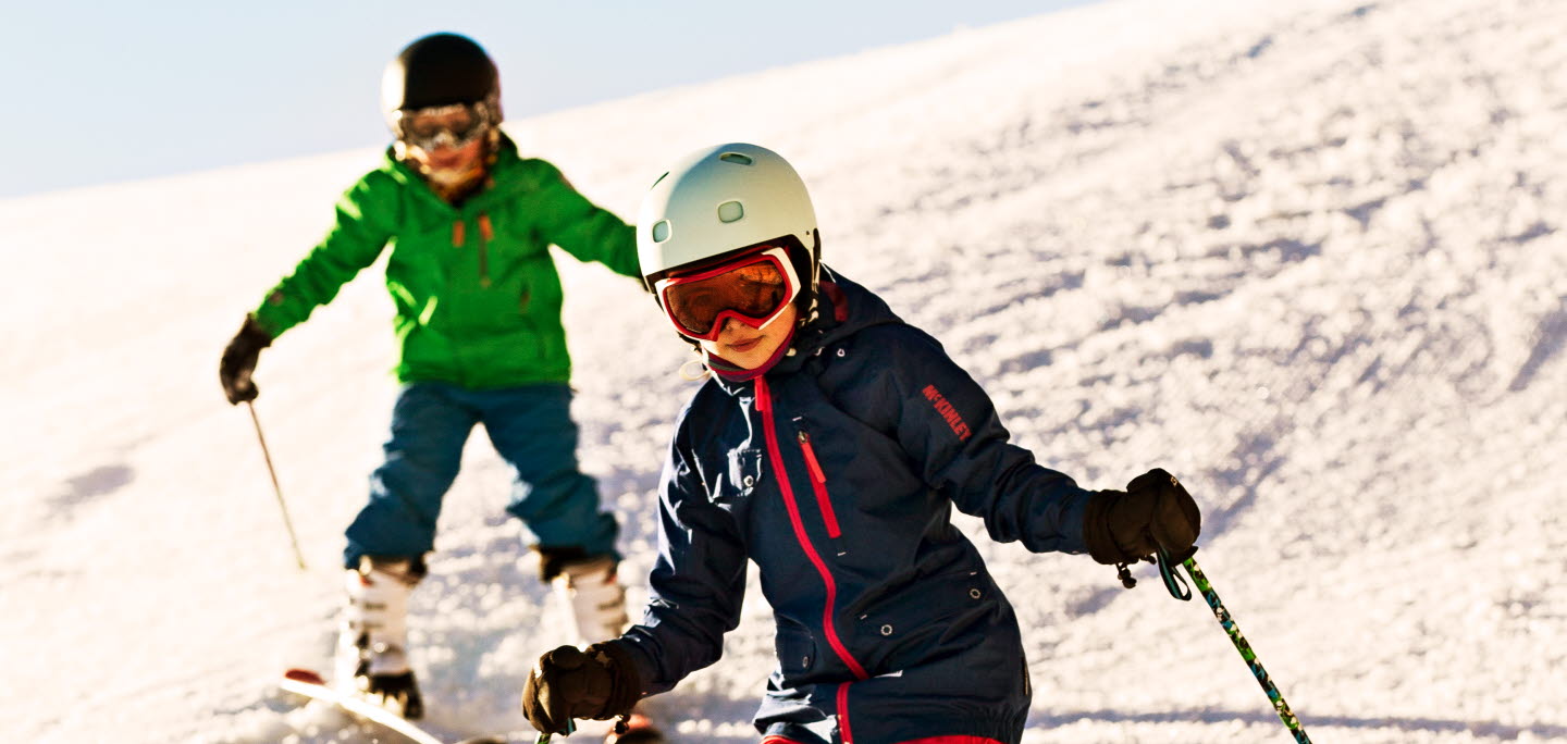 Två barn åker slalom i Bryngfjordens slalombacke.