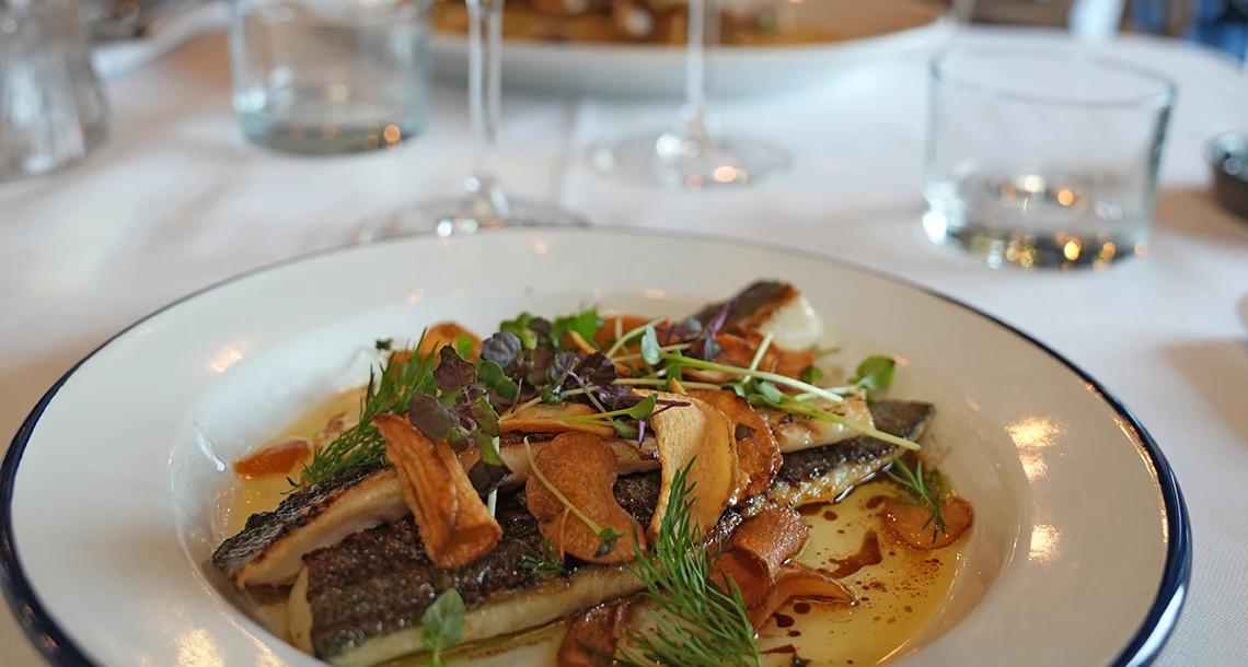 en maträtt med fisk och grönsaker upplagd på en tallrik