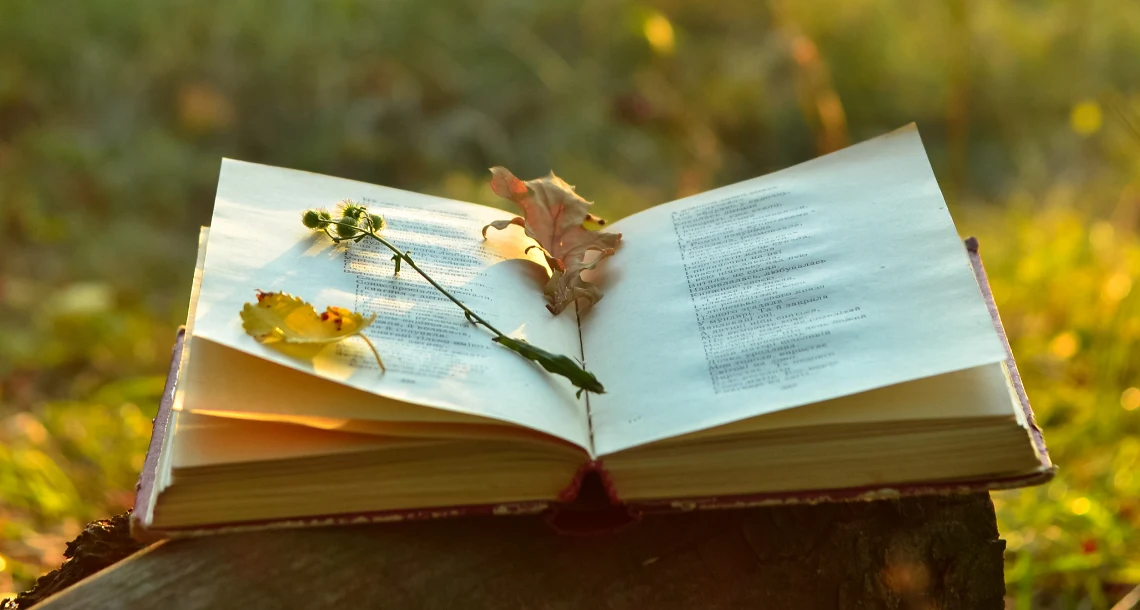 Uppslagen bok med löv och en blomma