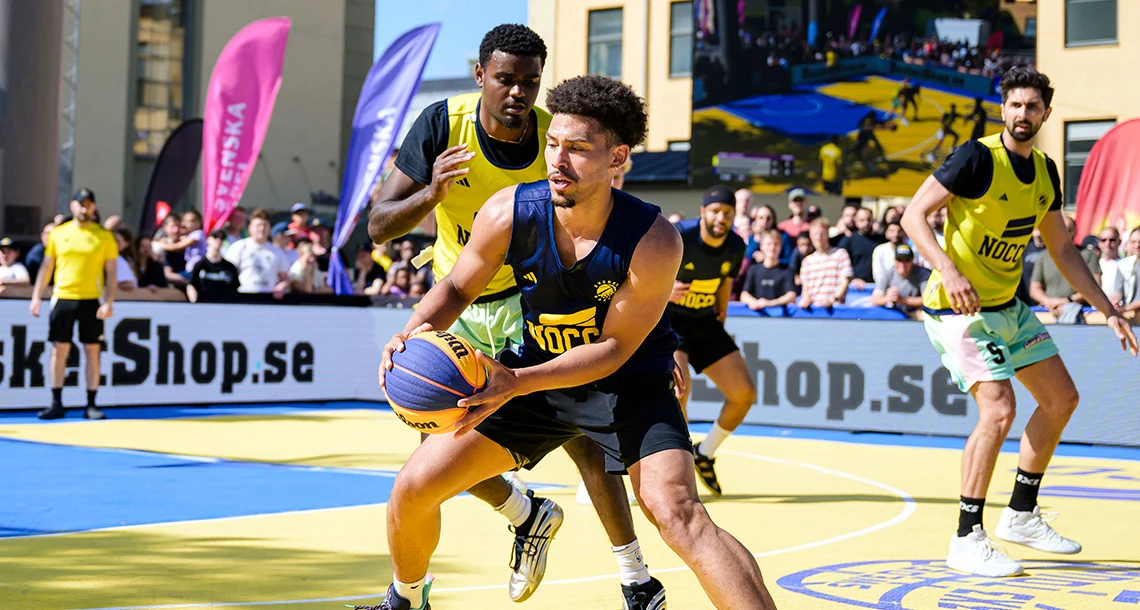 Tre killar i sportkläder spelar basket mot varandra