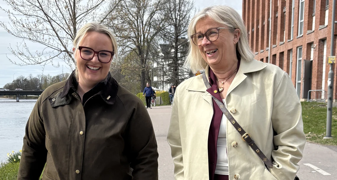 Två kvinnor som är glada går bredvid varandra på en cykelväg.