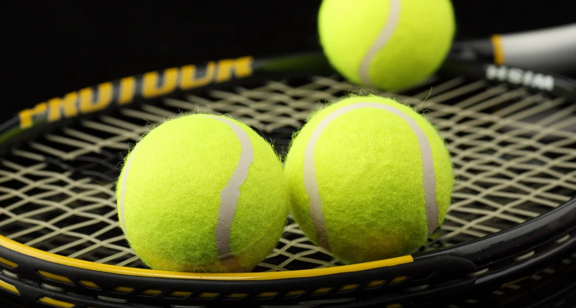 Tre tennisbollar på ett tennsirack