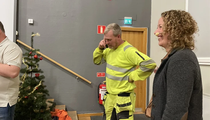 Man pratar i telefon och kvinna bredvid skrattar.