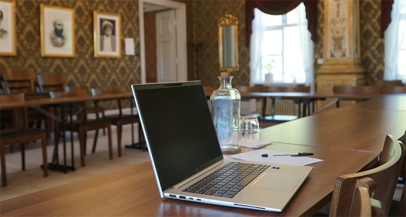 En närbild på en uppfälld laptop som står på ett bord bredvid en vattenflaska