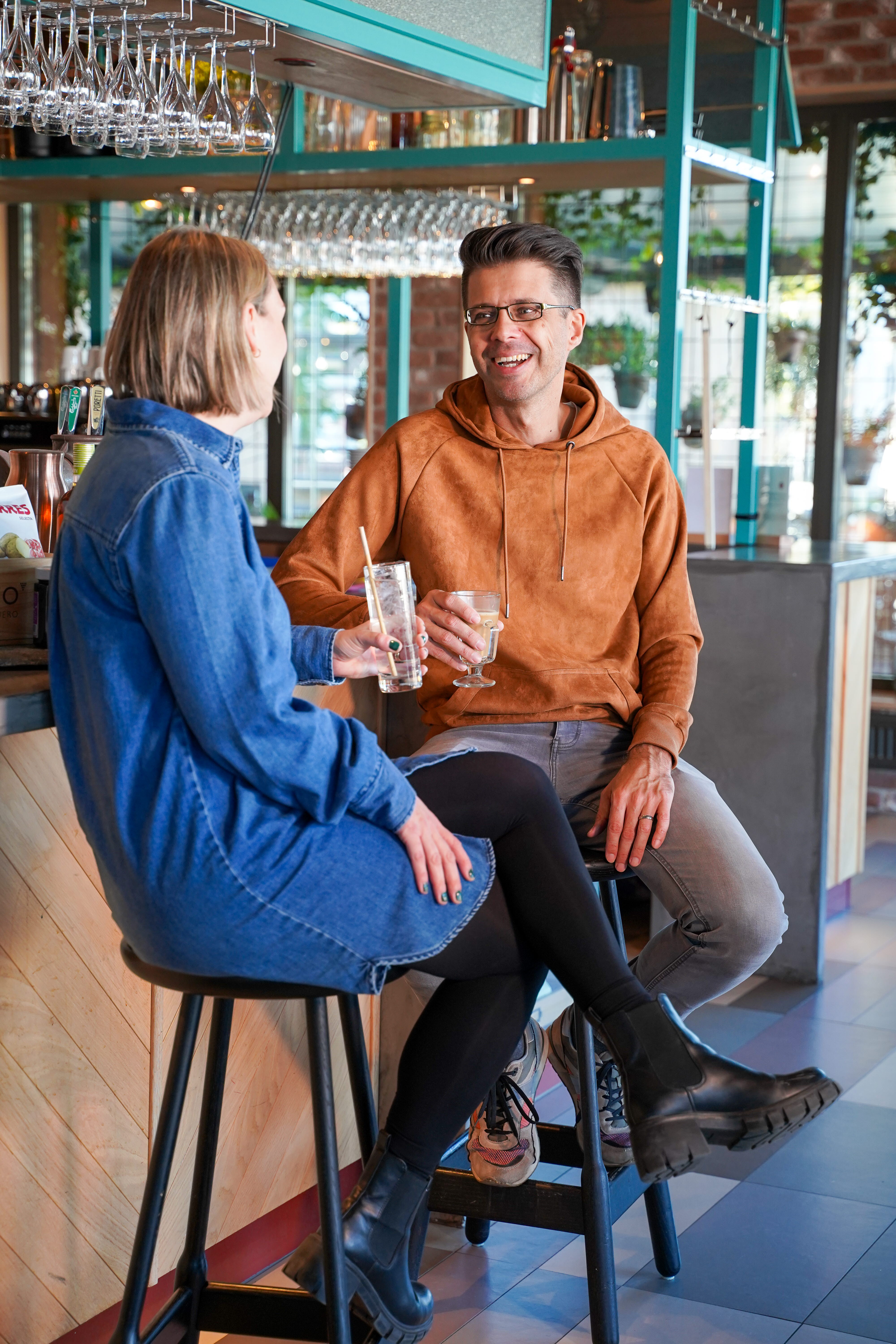 Närbild på två personer som sitter vid bardisken och dricker gott.