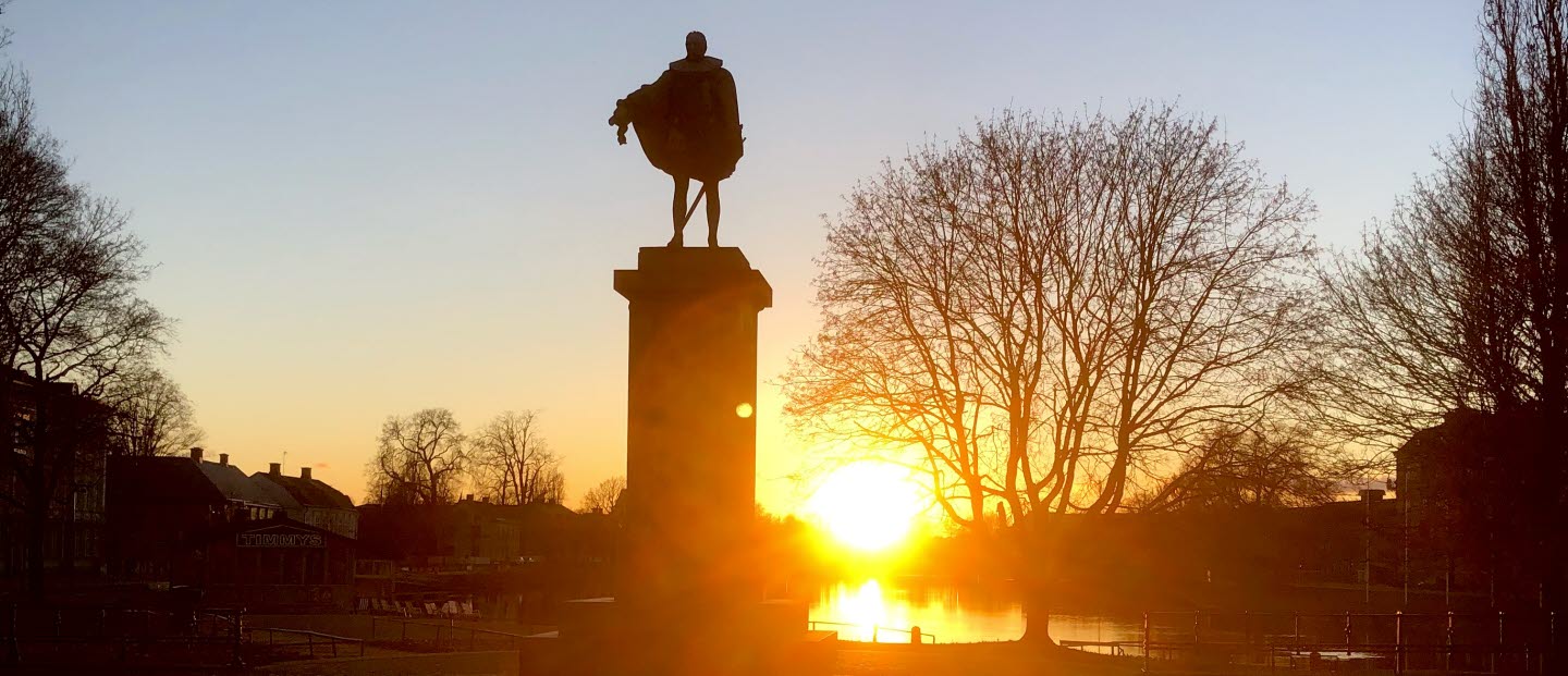 Solnedgång bakom siluetten av statyn av Karl IX