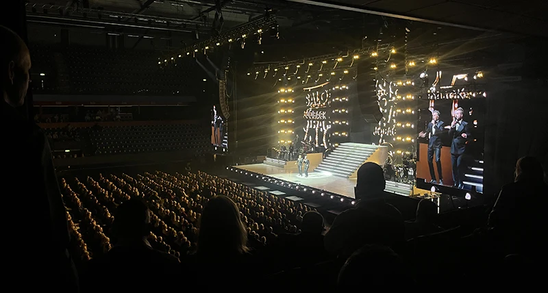 En konsert med flera människor på en stor scen med strålkastarljus framför en stor publik.